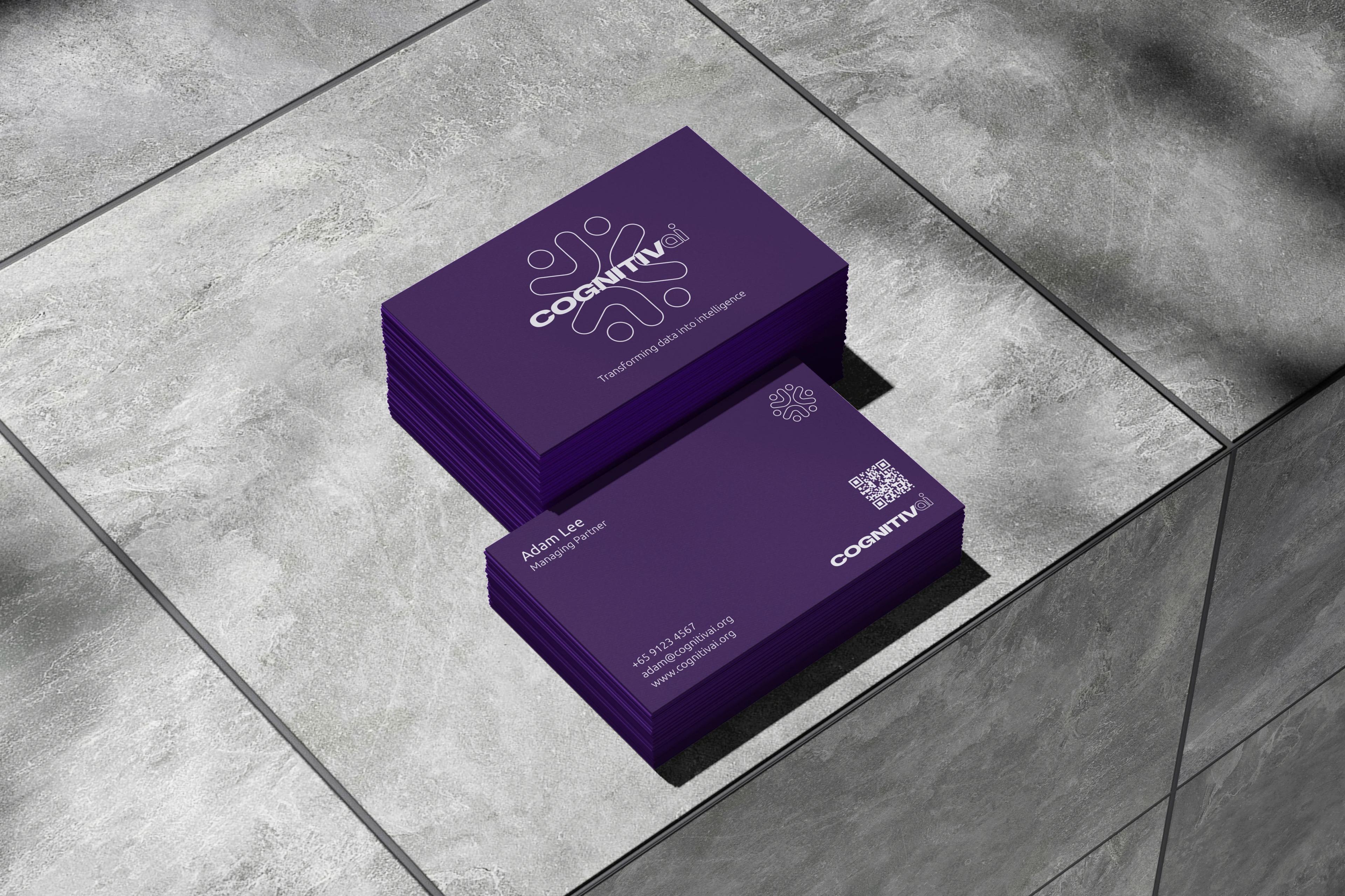 A stack of deep-purple business cards on a marble ledge, the top card showing the linked-figures monogram.