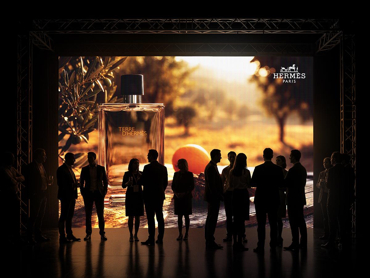 A wide backlit wall inside a truss-framed stage set, guests standing in silhouette against the golden grove.